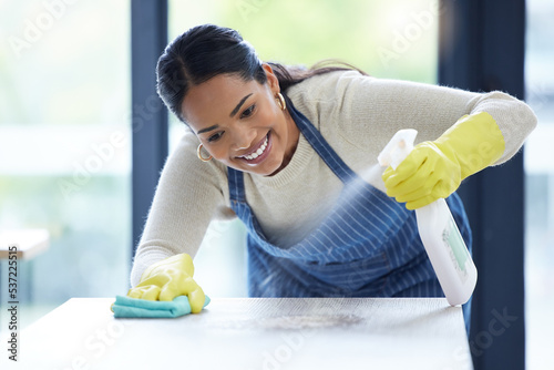 Woman spring cleaning table furniture with spray product, cloth and covid safety risk at home. Happy cleaner service, room and housekeeper dust with alcohol liquid solution in bottle for disinfection