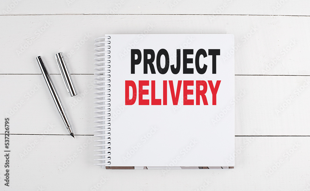 PROJECT DELIVERY text written on notebook on the wooden background PROJECT DELIVERY text written on notebook on the wooden background