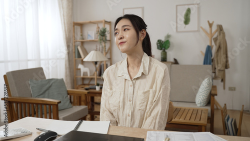 korean businesswoman is closing laptop and stretching with a smile feeling happy about meeting deadline while working from home in the living room