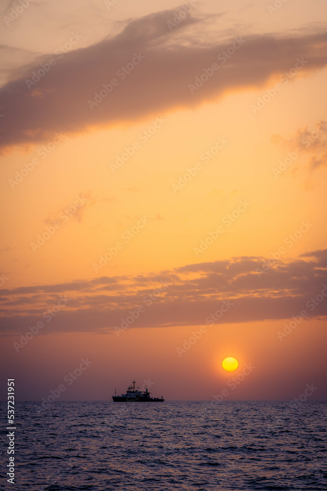 Boat in the distance during a warm summer sunset at the coast of Cyprus