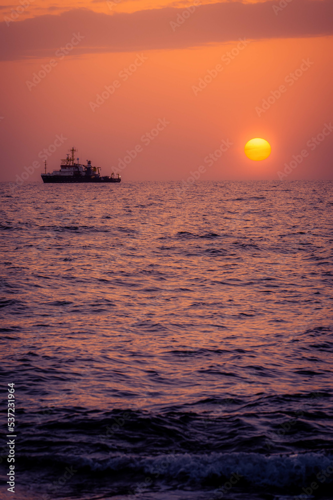 Boat in the distance during a warm summer sunset at the coast of Cyprus