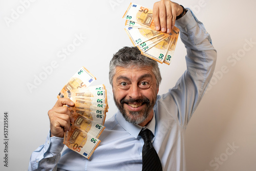 homme d'affaire souriant et heureux qui tient des liasses de billets dans ses mains. Il montre sa joie car il vient de gagner beaucoup d'argent photo