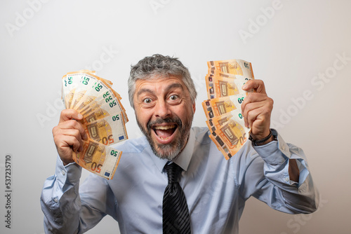 Foto homme d'affaire souriant et heureux qui tient des liasses de billets dans ses mains