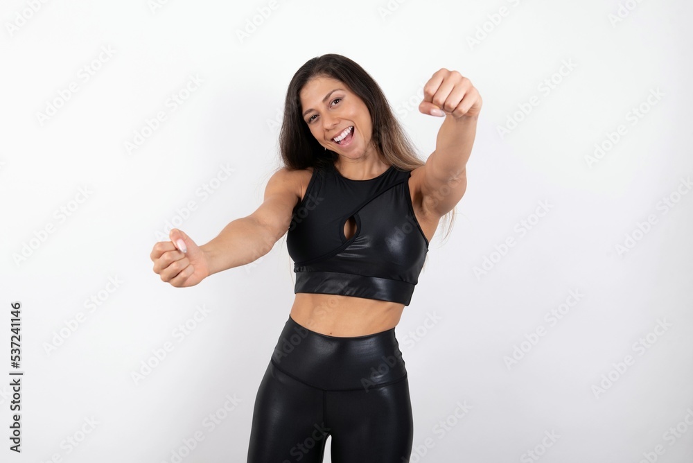 young beautiful woman wearing sportswear over white background imagine steering wheel helm rudder passing driving exam good mood fast speed young beautiful woman wearing sportswear over white background imagine steering wheel helm rudder passing driving exam good mood fast speed