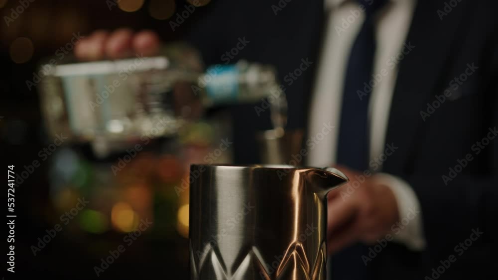The bartender pours alcohol into a metal measuring cup. Preparation of ingredients for a cocktail at the bar The bartender pours alcohol into a metal measuring cup. Preparation of ingredients for a cocktail at the bar