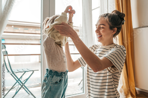 Slika na platnu Loving mother dressing her daughter by the window