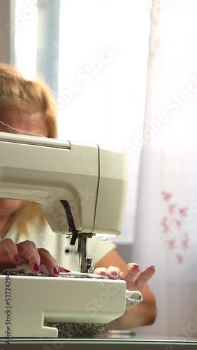 Sewing machine in the foreground with an older seamstress in the background - work and hobby concept