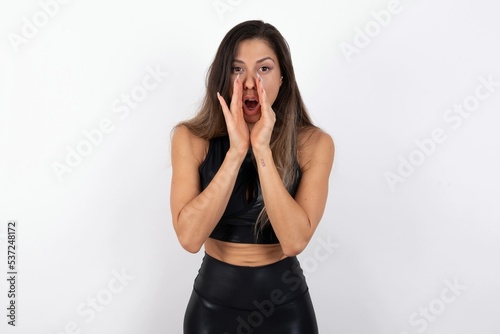 young beautiful woman wearing sportswear over white background shouting excited to front.