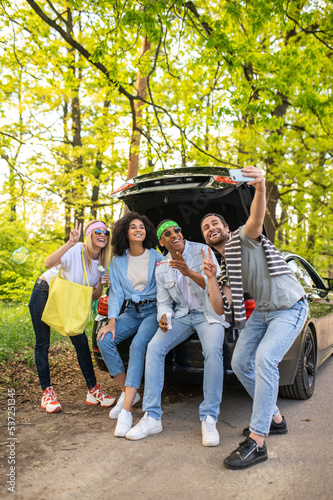 Group of friends making selfie in the forest while sitting on the car boot © zinkevych