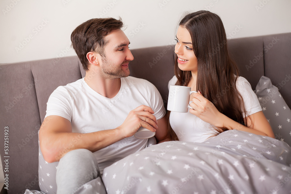 Happy sensual young couple lying in bed together