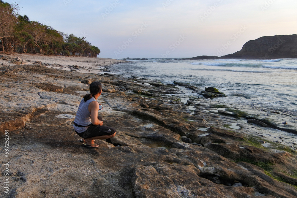 A Man enjoy and taking sunset photos around Papuma beach in Jember, East Java, Indonesia.