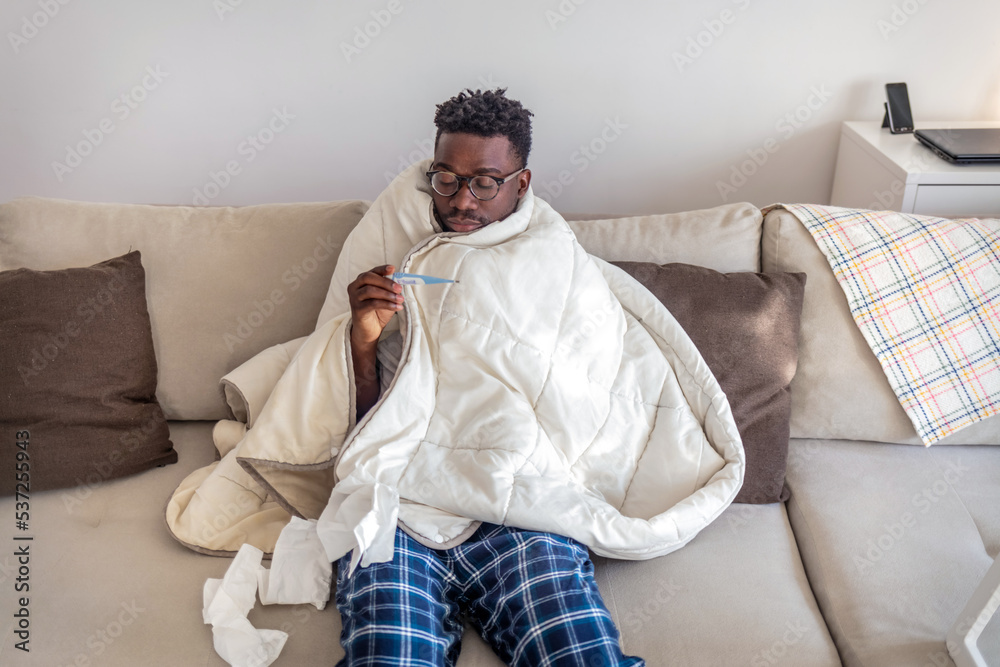 Portrait of a sick man with the flu, allergy, germs,cold coughing. Sick Man with headache sitting under the blanket with high fever and a flu, resting and drinking hot beverage. Portrait of a sick man with the flu, allergy, germs,cold coughing. Sick Man with headache sitting under the blanket with high fever and a flu, resting and drinking hot beverage.