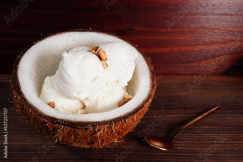 Coconut ice cream and halved coconut on wooden table (spot focus)