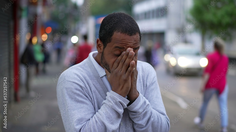 One anxious black man standing in urban street feeling nervous and stressed. Desperate African American rubbing hands in anxiety in modern sidewalk One anxious black man standing in urban street feeling nervous and stressed. Desperate African American rubbing hands in anxiety in modern sidewalk