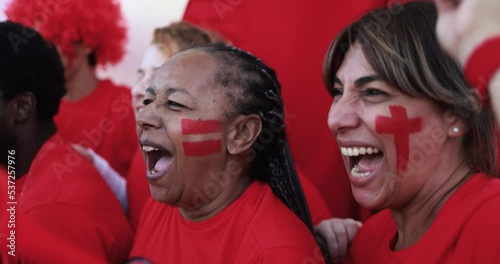 Latin red sport fans screaming while supporting their team - Football supporters having fun at competion event - Champions and winning concept photo