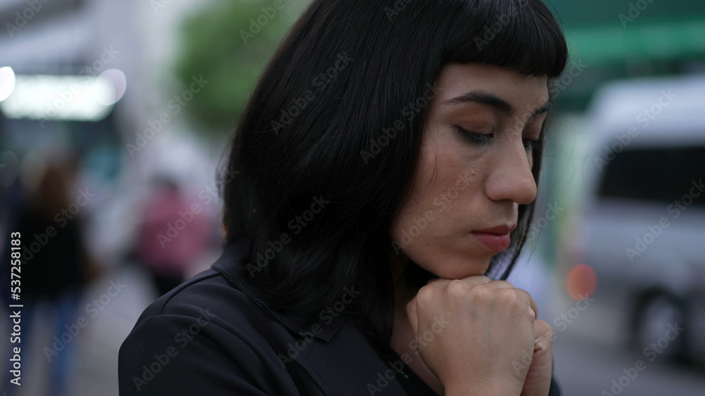 Lonely person standing in street looking down in sadness. One South American Brazilian hispanic young woman feeling solitude alone Lonely person standing in street looking down in sadness. One South American Brazilian hispanic young woman feeling solitude alone