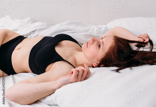 Portrait of a young beautiful brunette lying in bed wearing underwear