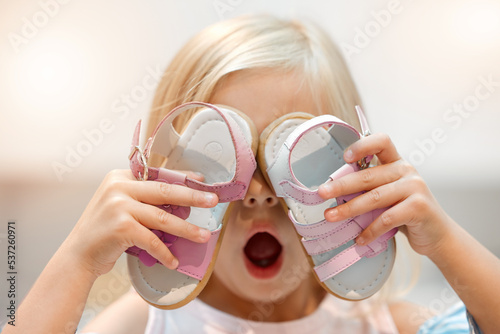 Girl child shopping for shoes, wow discount price in retail store and funny crazy face. Excited, young kid in boutique toddler sale, future footwear designer holding sandals and pink surprise gift