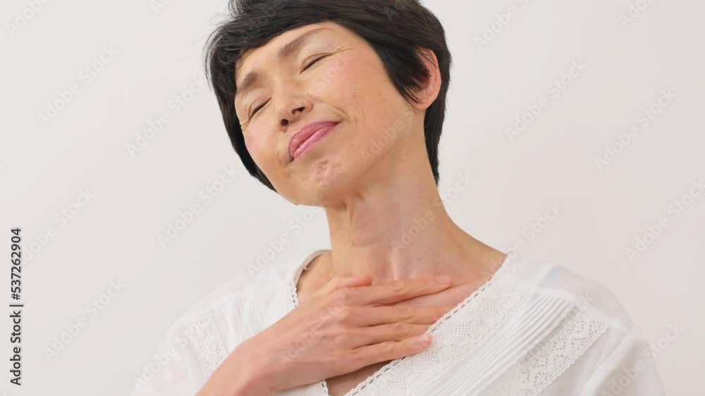 白背景で胸元をマッサージする中年女性