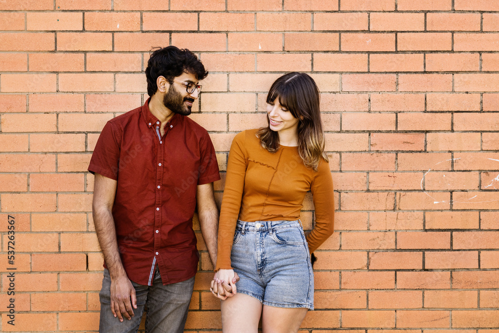 couple standing together leaning against brick wall couple standing together leaning against brick wall
