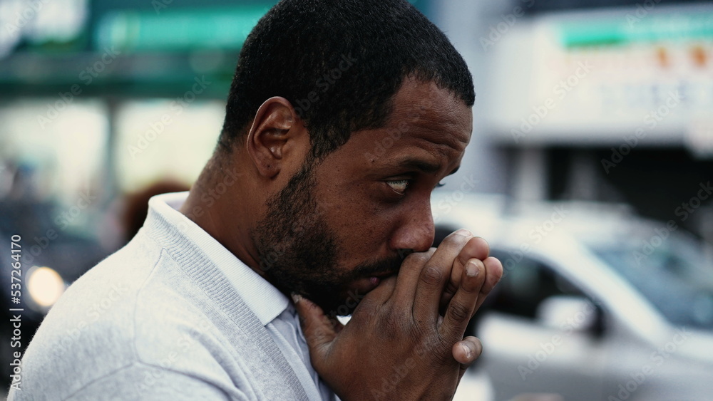 One spiritual young black man praying in street having HOPE and FAITH. African American prays in city urban sidewalk One spiritual young black man praying in street having HOPE and FAITH. African American prays in city urban sidewalk