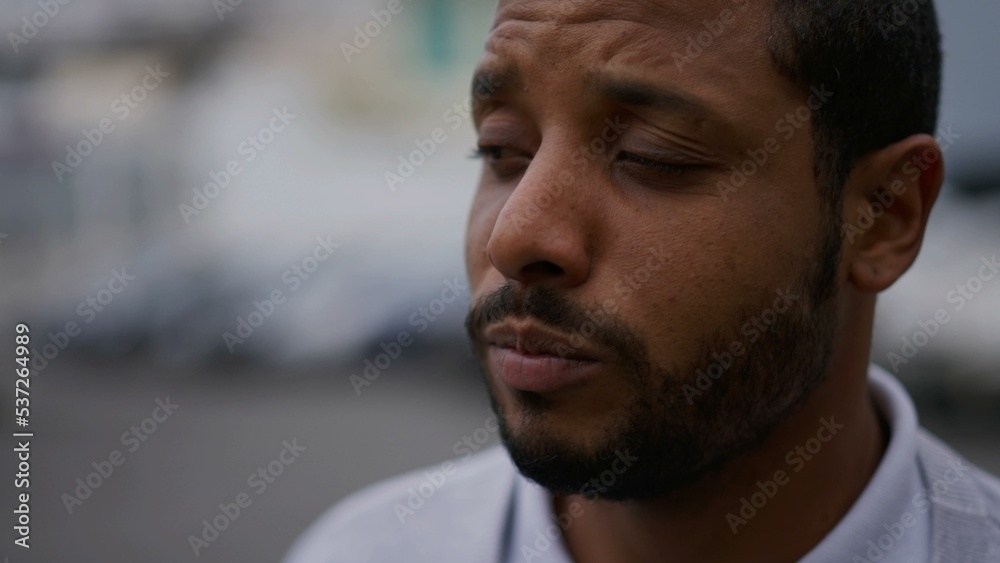 Fototapeta premium One anxious young African American man in distress closeup face. Portrait of a black person with worried preoccupied emotion