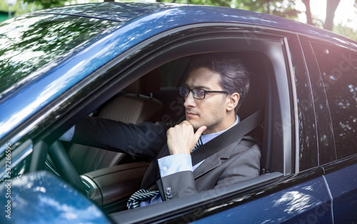 Handsome businessman in black suit driving in luxury car © Vitaliy