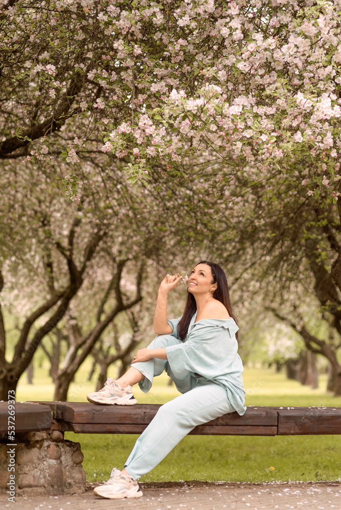 Naklejka premium girl with long dark hair in spring blooming garden