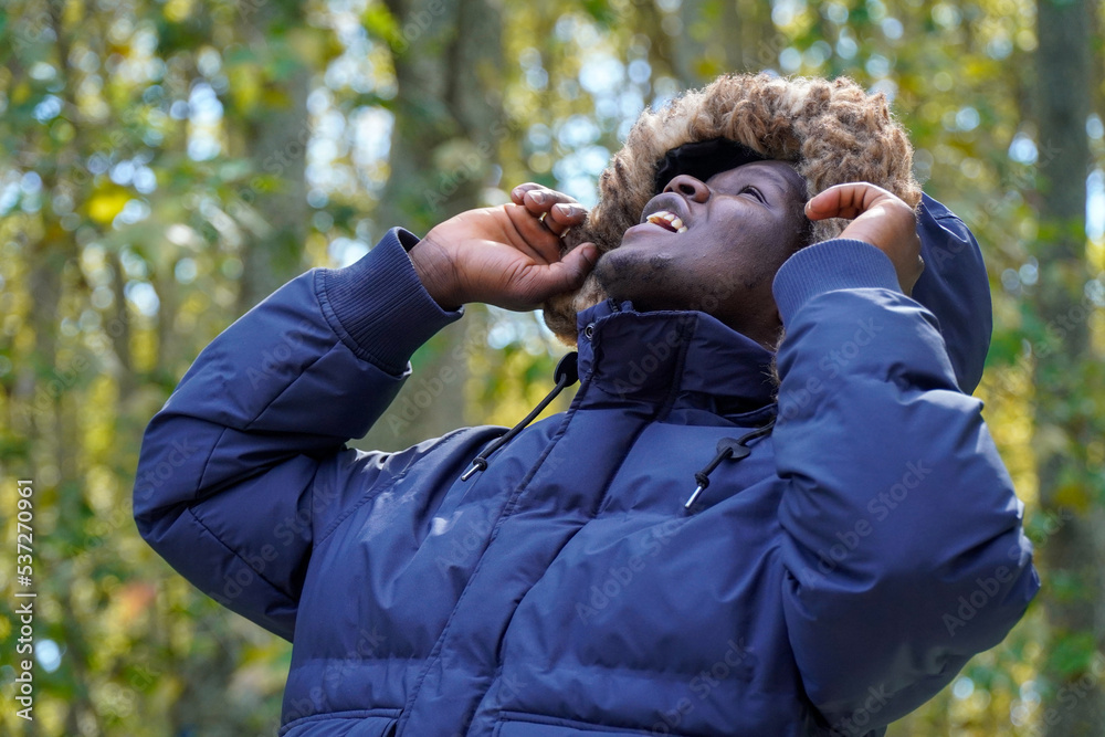 Black man with winter coat with hood looking up. wintertime fashion. Black man with winter coat with hood looking up. wintertime fashion.
