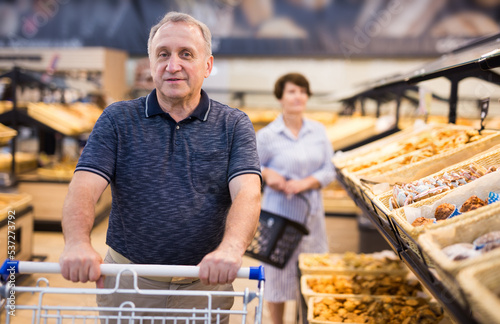 Mature man examines bakery products in the grocery section of the supermarket
