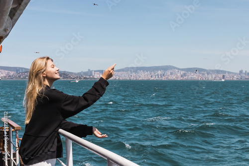 Photography happy woman in black sweater gesturing and looking at sea from ferry boat crossing bosphorus strait