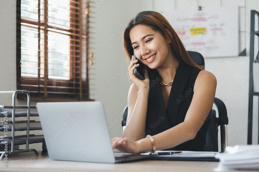 Asian woman talking on the phone, she is a salesperson in a startup company, she is calling customers to sell products and promotions. Concept of selling products through telephone channels.