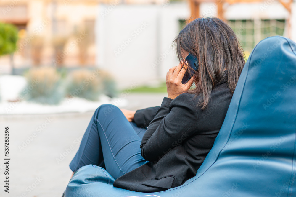 Young caucasian woman at cafe sitting on the bean bag chair talking on the mobile phone.business remote concept.
