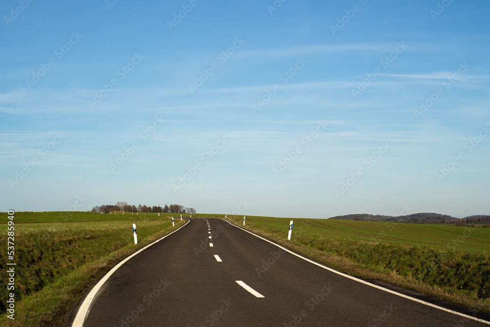 View of a rural road in the landscape with blue sunny sky in january