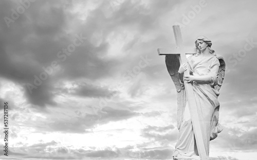 Tombstone angel with wings and cross on sky background