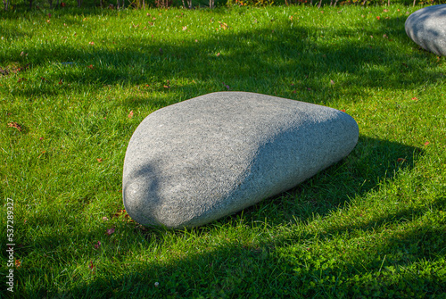 gray granite boulder on a green lawn