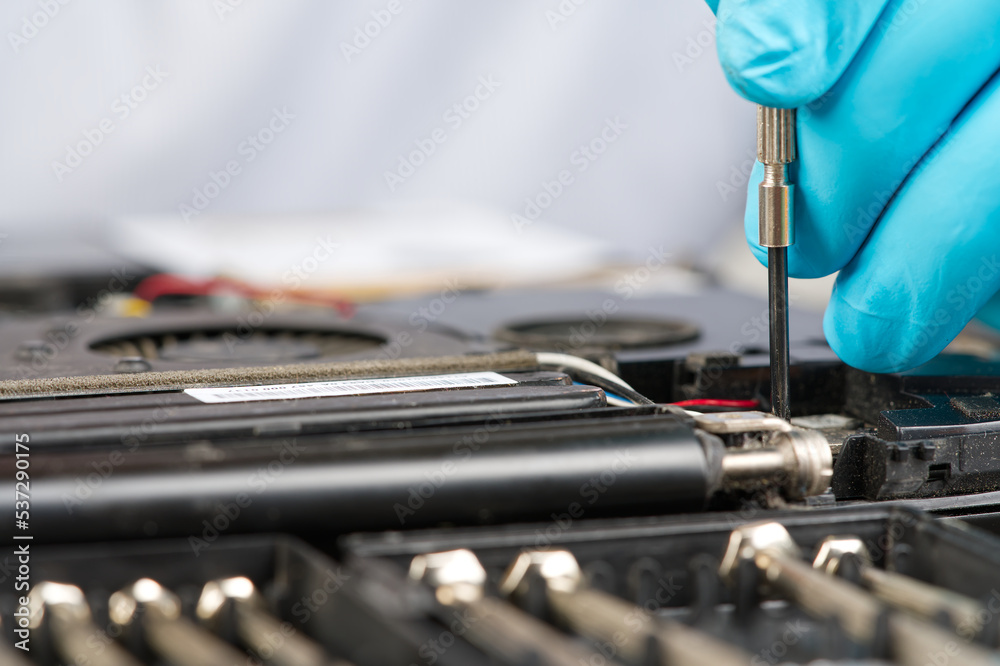Hands of a technician repairing a broken laptop computer. Laptop repair service. Engineer fixing broken notebook. Computer technology. Laptop disassembling in repair shop, close-up. Hands of a technician repairing a broken laptop computer. Laptop repair service. Engineer fixing broken notebook. Computer technology. Laptop disassembling in repair shop, close-up.