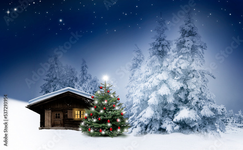 Glänzender Weihnachtsbaum bei einer Blockhütte im Schnee