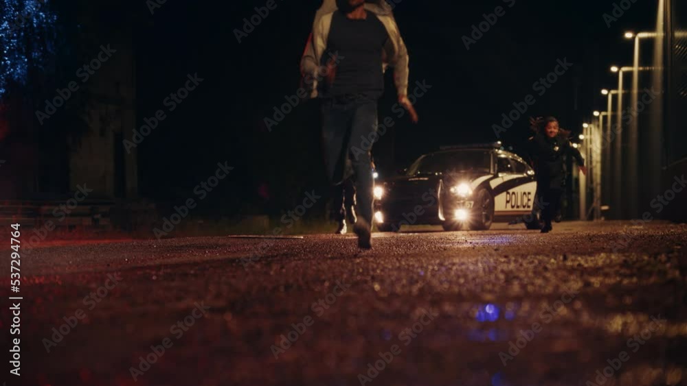 Two Police Officers in Pursuit of a Suspect. Cops Getting out of the Car Chase Criminal Through the Dark City Streets. Heroic Officers of the Law Arresting Felon. Intense Cinematic Slow Motion