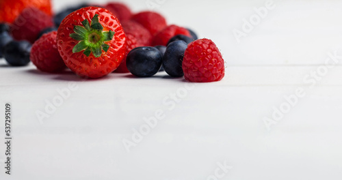 Close-up of strawberry with blueberries and raspberries against white background, copy space