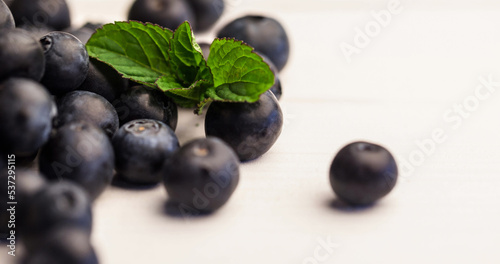 Close-up of fresh blueberries and leaves against white background, copy space