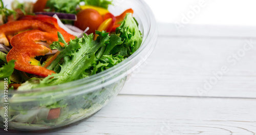Close-up of fresh vegetable salad in glass bowl over wooden table, copy space