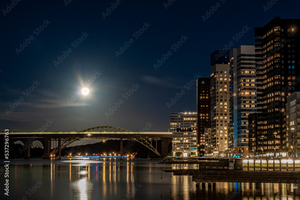 Naklejka premium Stockholm, Sweden The Liljeholmskajen district at night with a full moon.