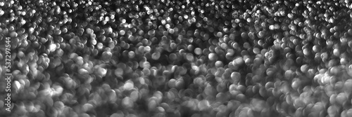 Gray black sparkling glitter bokeh background, christmas abstract defocused texture. Holiday lights. Snowy shiny sparkle stars header. Wide screen wallpaper. Panoramic web banner with copy space