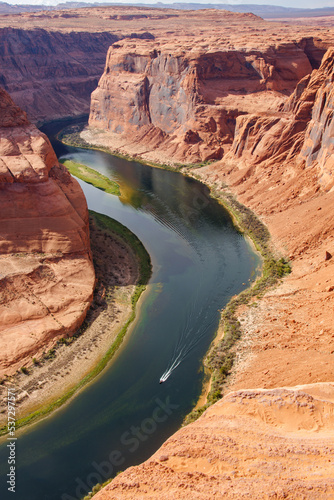 View of Horseshoe Bend of Colorado river with a motor boat in the river