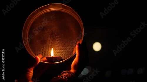 Woman hand holding Karwa Chauth strainer for the Karwa Chauth celebration on the night. Karwa Chauth strainer and Diya oil lamps for the Karwa Chauth celebration on the night photo