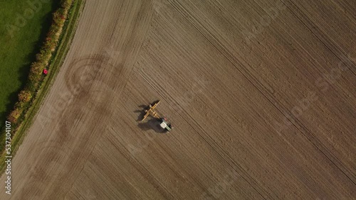 A tractor rolling a ploughed field in Autumn. From directly above.  Aerial