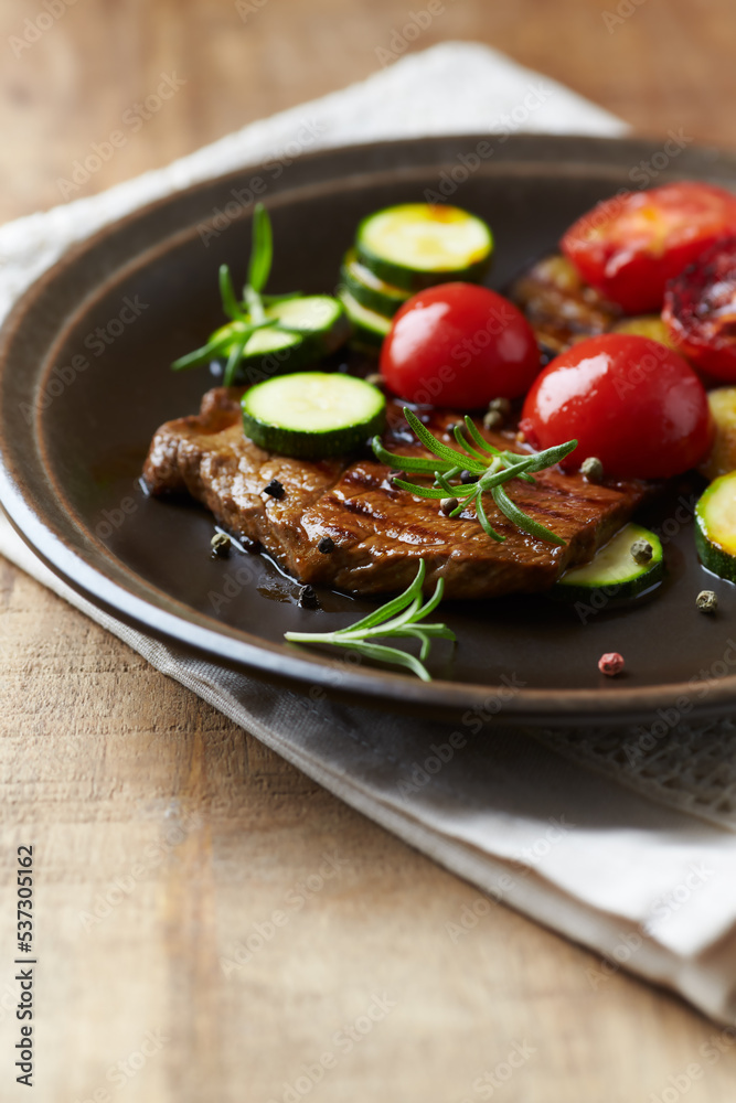 Grilled beef steak with tomatoes and fresh herbs. Copy space.