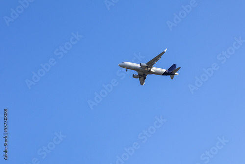 Airplane in blue sky with light clouds over the house
