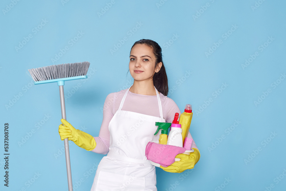 woman in gloves and cleaner apron holding bucket of detergents and broom woman in gloves and cleaner apron holding bucket of detergents and broom